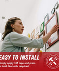 Person installing frames on wall using 3M 5925 Black Double Sided Foam Tape 0.5 Inch By 18 Feet Heavy Duty Waterproof Mounting Tape.