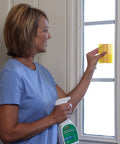 Person using Complete Window Film Installation Kit For Residential Use With Ready To Use 16oz Cleaning Solution Sprayer on glass.