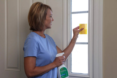 Person using Complete Window Film Installation Kit For Residential Use With Ready To Use 16oz Cleaning Solution Sprayer on glass.