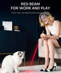 Woman using flashlight with red beam to play with a white cat indoors, showcasing versatility for work and play.