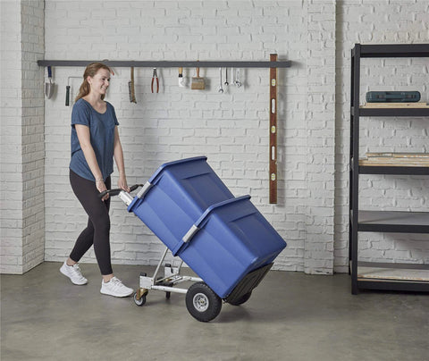 Person using ✝️ COSCO 4-in-1 Folding Series Hand Truck with Flat-Free Wheels carrying a large blue container in a garage.