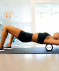 Woman using Medium Compression Foam Roller For Myofascial Release Massage With Three Texture Zones for muscle recovery on mat
