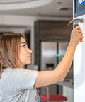 Person using bulk picture hanging kit with 600 galvanized nails in four sizes plus an 8 ounce hammer to hang a frame.