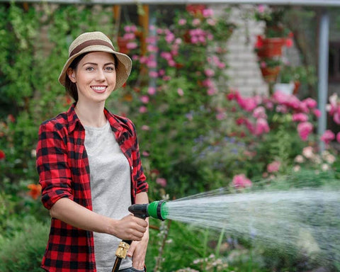 Person using a garden hose equipped with Garden Hose Quick Connect Fittings Set 3/4 Inch GHT Solid Brass Connectors watering plants.