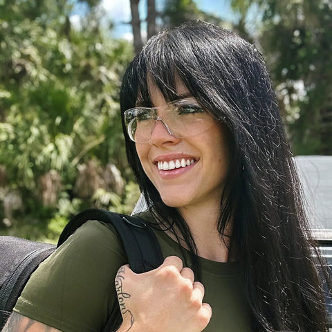 Woman wearing pink protective safety glasses for women and youth, small fit for lab and cycling, outdoors smiling.