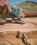 Person using Extreme Shaping Disc for Woodworking Coping with Angle Grinder Attachment on wood surface outdoors