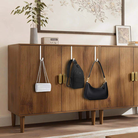 Wooden cabinet with bags hanging from hooks, placed in a modern, elegantly decorated room with a wall art and plant vase on top.