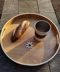 16 Inch Lazy Susan Turntable With Handles Wooden Rotating Tray With Raised Rim holding bread and cup on stone surface