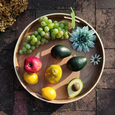 Top view of 16 Inch Lazy Susan Turntable With Handles Wooden Rotating Tray With Raised Rim displaying fruits and flowers.
