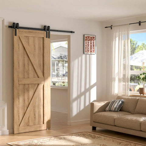 Sliding wooden barn door in living room with sunlight, adjacent to a beige sofa and large window