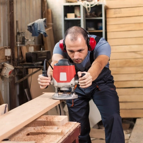 Woodworker uses router in workshop; ideal for Five Sixteenth Inch Internal Threaded Clamping Knobs for precise routing setups