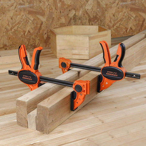 Two Pack Six Inch One Hand Clamp And Spreader Set With 300 Lb Clamping Force holding wooden planks on a workbench