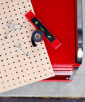 Pegboard with hooks and level placed next to Extreme Double Sided Mounting Tape 414H, near a red tool cart.