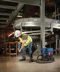 Worker using One And One Eighth Inch SDS-Plus Bulldog Xtreme Max Rotary Hammer for concrete drilling in a factory setting.