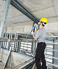 Worker using One And One Eighth Inch SDS-Plus Bulldog Xtreme Max Rotary Hammer for concrete drilling in a construction site.