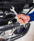 A hand holding a wrench near a car engine, using Three Pack 18G Grease Gun Needles For Easy Lubrication Of Machines And Bicycle Chains.