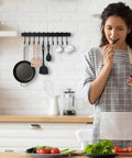 Wrought Iron Kitchen Holder: 10-Hook Wall-Mounted Utensil Rack with Black Finish displayed in kitchen with woman preparing food