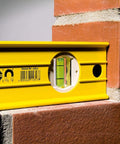 Stabila 37424 24 Inch Builders Level With High Strength Box Frame for framing tile and trim work, bright vials visible on brick wall