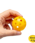 Hand holding a yellow 40mm Practice Golf Training Ball, Limited Flight, Hollow Plastic Airflow. Part of 12-pack mixed color set for home use.