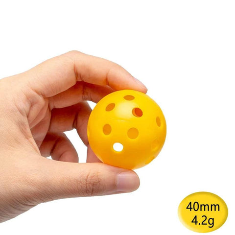 Hand holding a yellow 40mm Practice Golf Training Ball, Limited Flight, Hollow Plastic Airflow. Part of 12-pack mixed color set for home use.