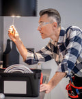 Man wearing ANSI Z87 Safety Glasses With Impact-Resistant Lenses And UV Protection 12-Pack while working on electrical task indoors.