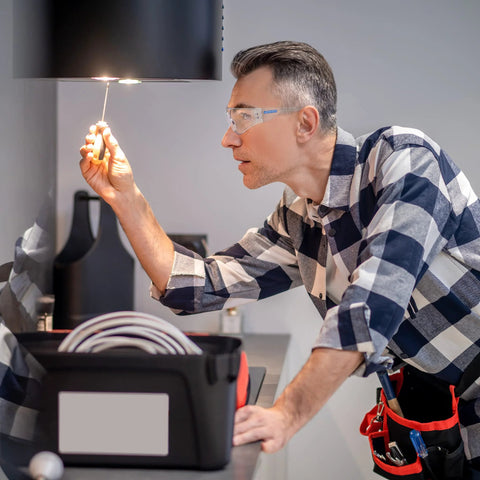 Man wearing ANSI Z87 Safety Glasses With Impact-Resistant Lenses And UV Protection 12-Pack while working on electrical task indoors.