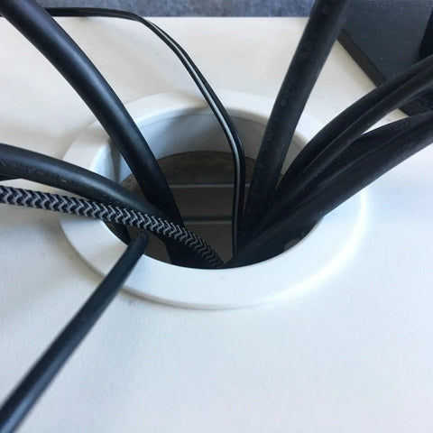 Close-up of a zinc alloy desk hole cover grommet guiding cables, designed to fit standard desk openings for a tidy, professional look.